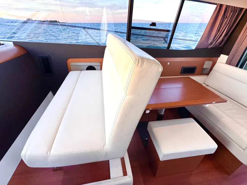 Slide: The Image of Interior of a 2017 Jeanneau NC 11 with white upholstered seating and a wooden table. - 39