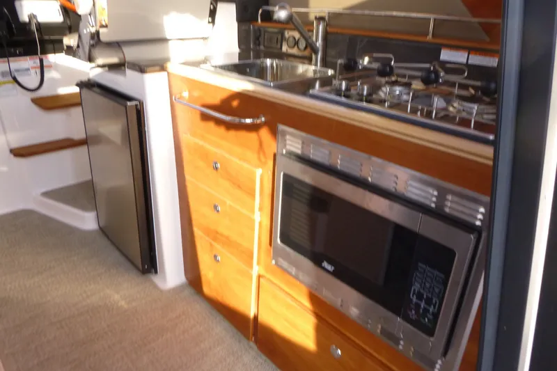 Slide: The Image of 2025 Cutwater C-288 Coupe interior kitchen with stove, microwave, and fridge. - 21