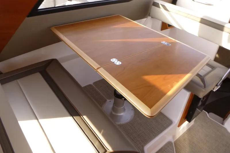 Slide: The Image of Interior of 2025 Cutwater C-288 Coupe featuring a wooden dining table and cushioned seating. - 14