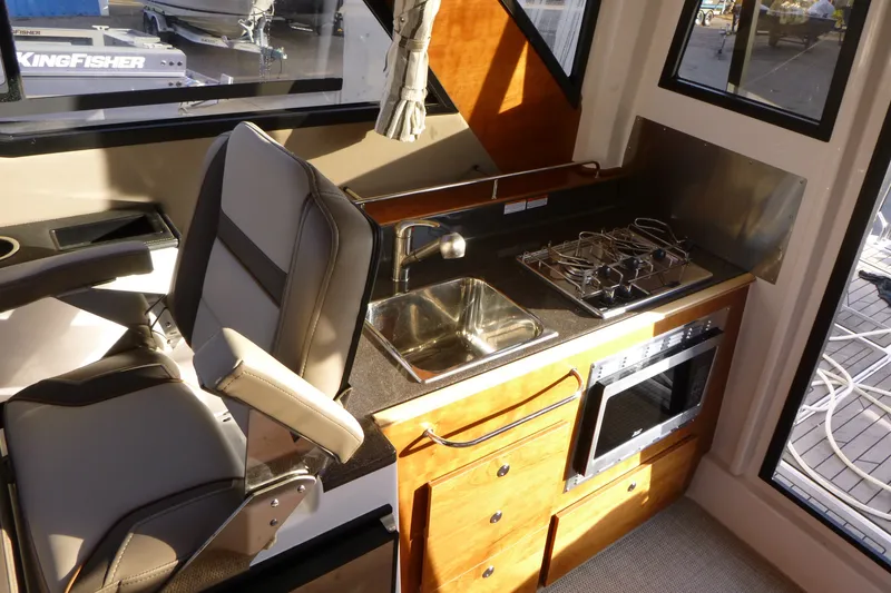 Slide: The Image of Interior of 2025 Cutwater C-288 Coupe featuring a compact kitchen with stove and sink. - 20
