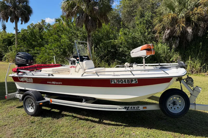 The Image of 2013 Mako Pro Skiff 16 CC boat on trailer, surrounded by lush greenery. - 0