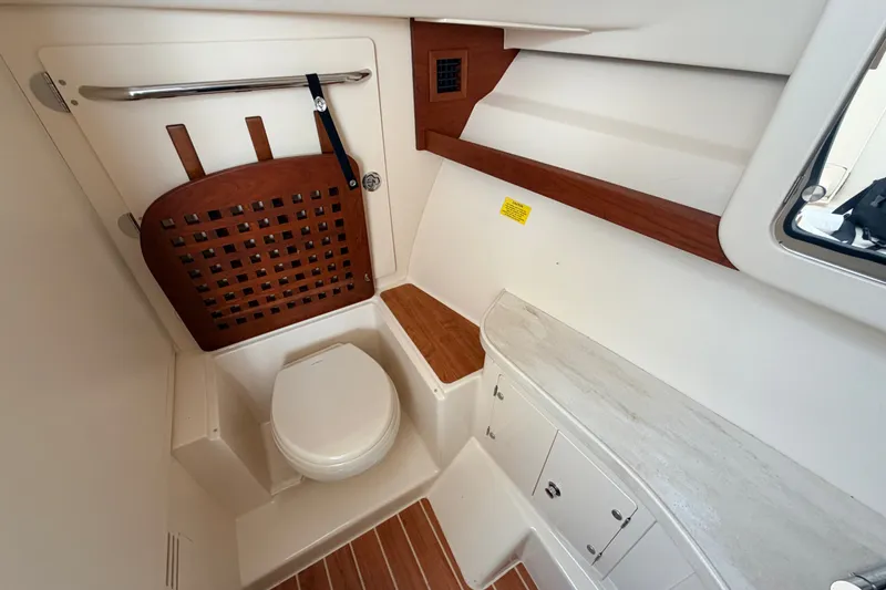 Slide: The Image of Interior of 2021 Grady-White Freedom 335 boat, featuring a compact marine toilet area. - 24