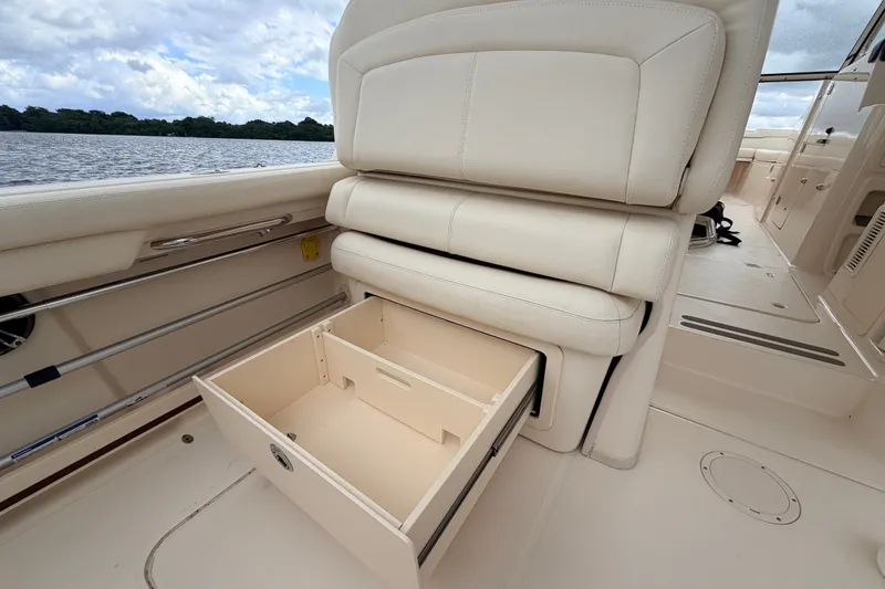 Slide: The Image of 2021 Grady-White Freedom 335 boat interior with open storage drawer, white seating, and scenic water view. - 28
