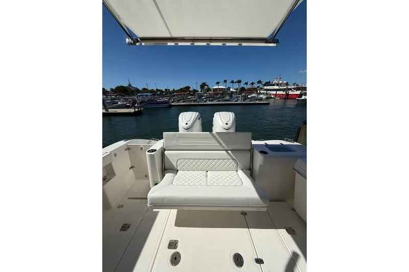 Slide: The Image of 2025 Pursuit S 328 Sport boat interior with seating, docked at marina under clear sky. - 7
