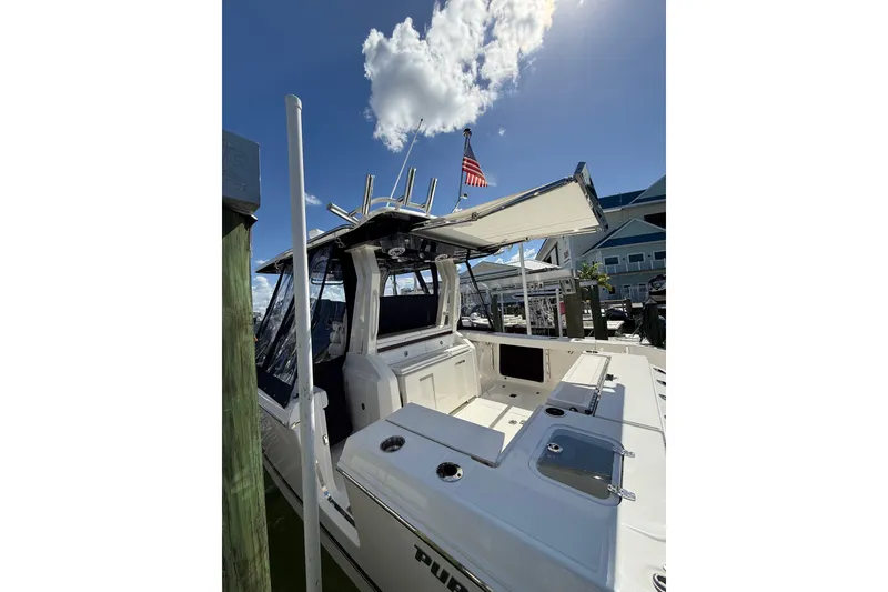 Slide: The Image of 2025 Pursuit S 328 Sport boat docked under clear blue sky with American flag. - 12