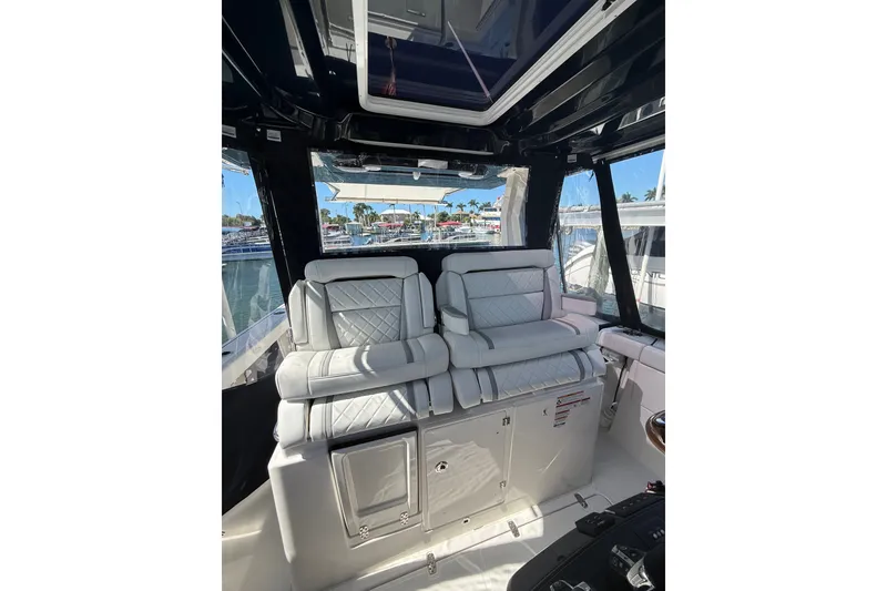 Slide: The Image of 2025 Pursuit S 328 Sport boat interior with luxurious white seating and marina view. - 9