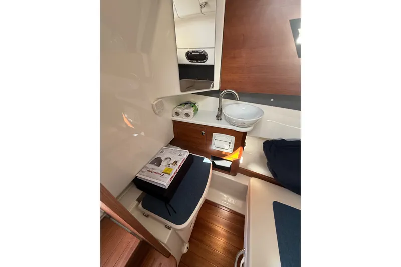 Slide: The Image of 2025 Pursuit S 328 Sport cabin interior with sink, seating, and wooden accents. - 15