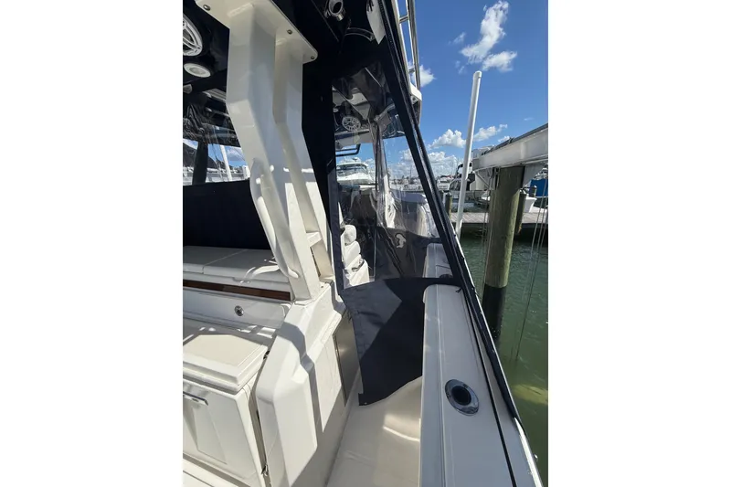 Slide: The Image of 2025 Pursuit S 328 Sport boat interior with seating, docked under clear blue sky. - 8
