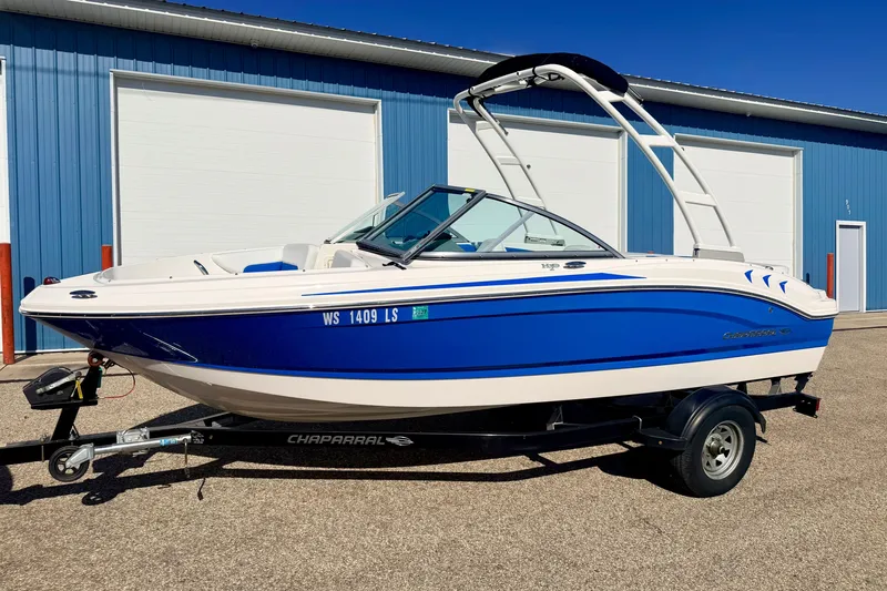 Slide: The Image of 2017 Chaparral 19 Sport H2O boat in blue and white, parked on a trailer. - 7
