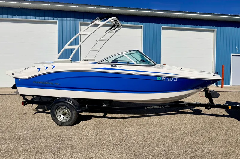 Slide: The Image of 2017 Chaparral 19 Sport H2O boat in blue and white, parked on a trailer. - 3