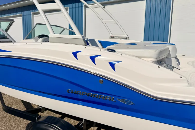 Slide: The Image of 2017 Chaparral 19 Sport H2O boat with blue and white design, parked outdoors. - 11