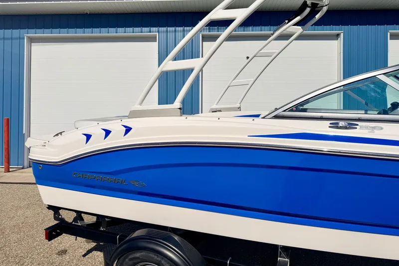 Slide: The Image of 2017 Chaparral 19 Sport H2O boat with blue and white design, parked near a blue building. - 18