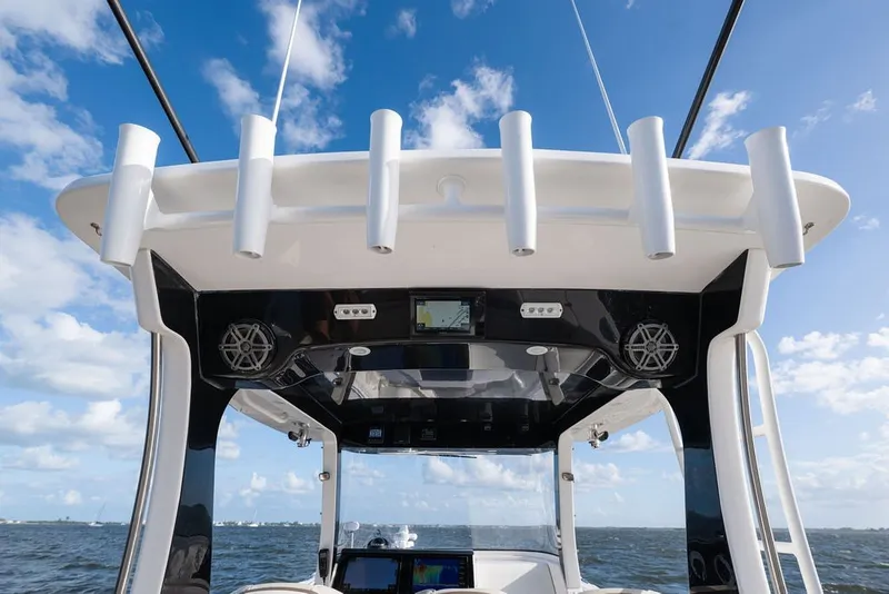 Slide: The Image of 2020 Edgewater 370CC boat helm with rod holders and electronics against blue sky. - 28