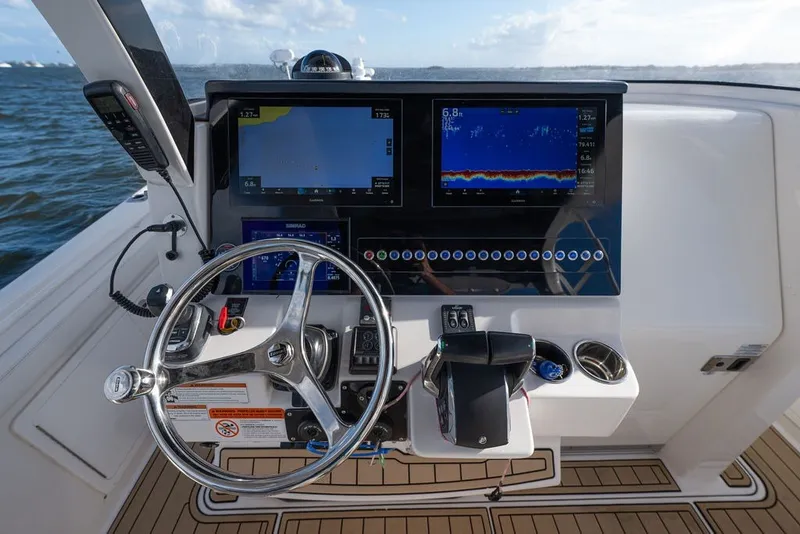 Slide: The Image of 2020 Edgewater 370CC helm with dual navigation screens and steering wheel on open water. - 33