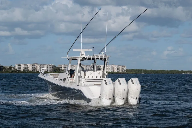 Slide: The Image of 2020 Edgewater 370CC boat cruising on water with four engines, under a cloudy sky. - 5
