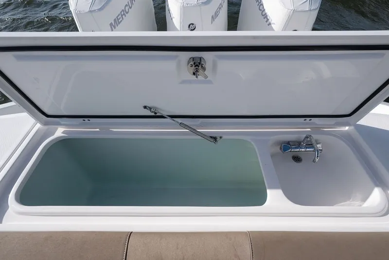 Slide: The Image of Open storage compartment on 2020 Edgewater 370CC boat with faucet and Mercury engines visible. - 46