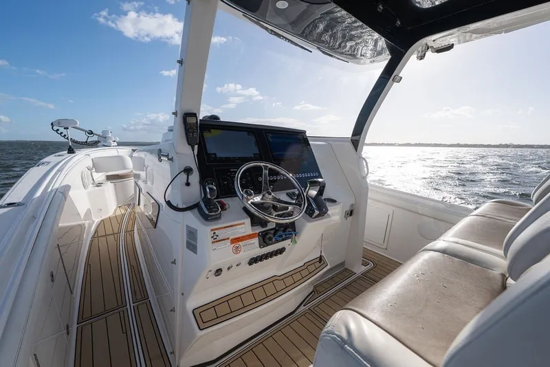Slide: The Image of 2020 Edgewater 370CC boat interior with helm, steering wheel, and ocean view. - 18