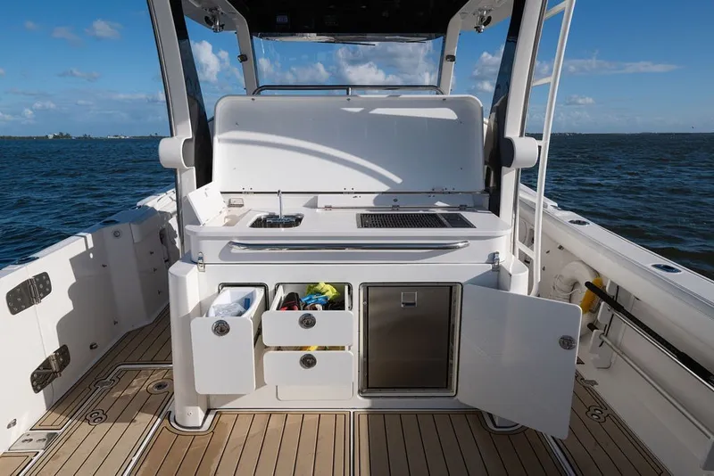 Slide: The Image of 2020 Edgewater 370CC boat with open storage compartments and sink, on a sunny day at sea. - 50
