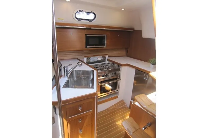 Slide: The Image of Modern Catalina 386 yacht kitchen with wood finish, stainless steel appliances, and ample counter space. - 24