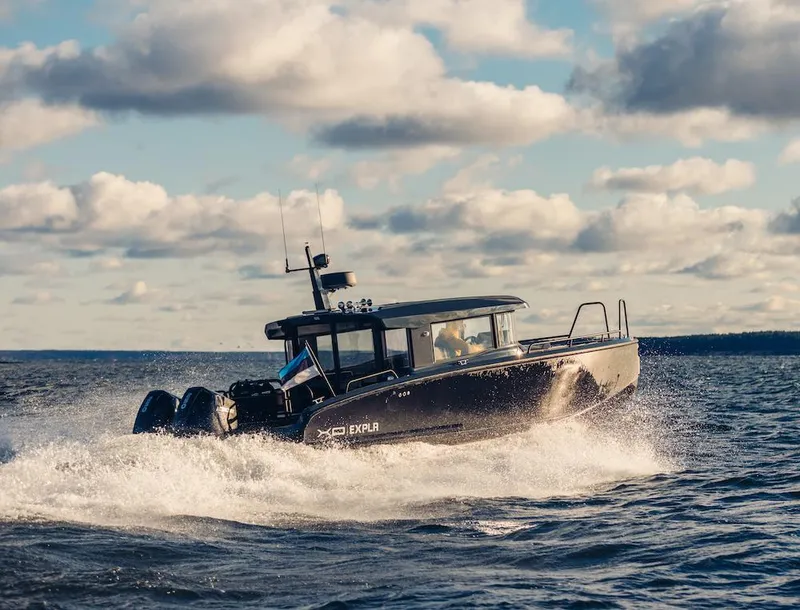 The Image of 2024 XO Boats EXPLR 10S cruising on open water under a partly cloudy sky. - 0