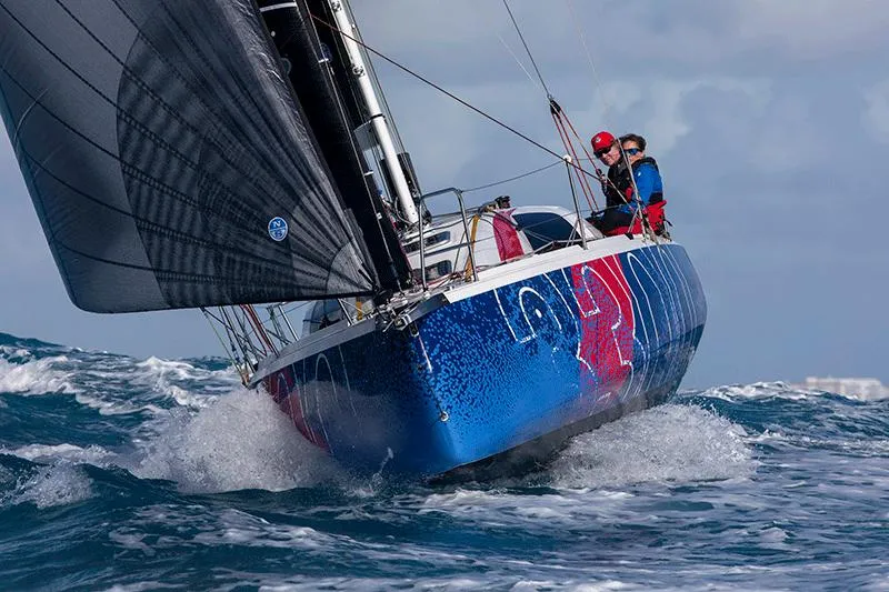 Slide: The Image of 2025 Jeanneau Sun Fast 3300 sailing on rough seas, vibrant blue and red hull. - 13
