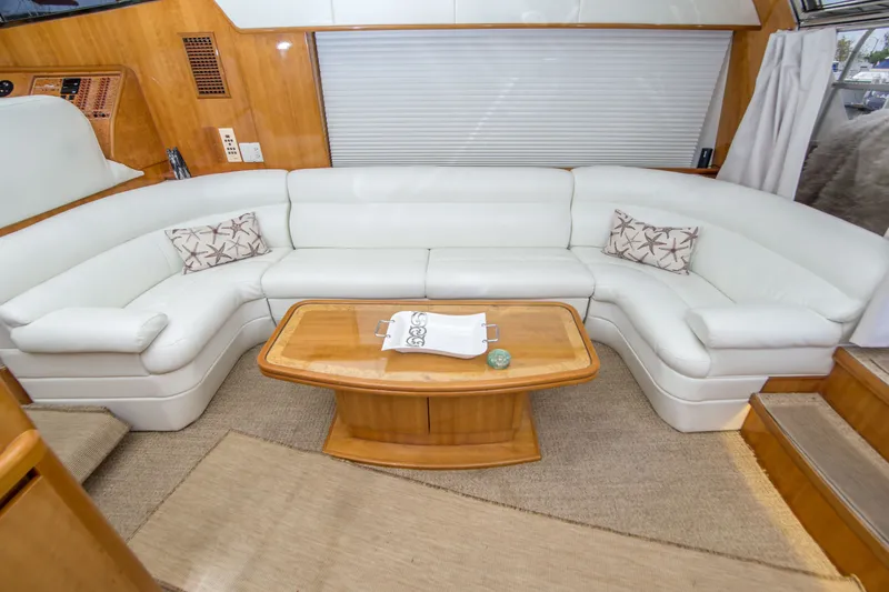 Slide: The Image of Luxurious yacht interior with white leather seating, wooden table, and nautical-themed pillows. Johnson 58, 2000. - 26