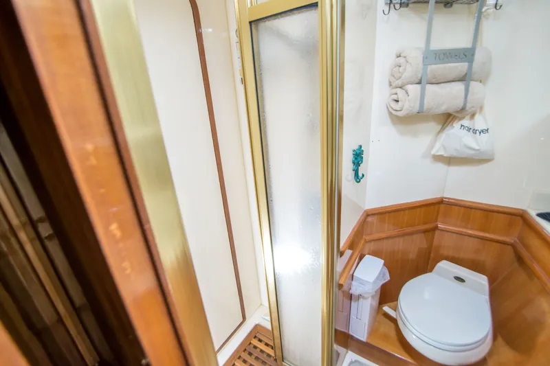 Slide: The Image of Compact yacht bathroom with shower, toilet, and towel storage on a 2000 Johnson 58 model. - 16