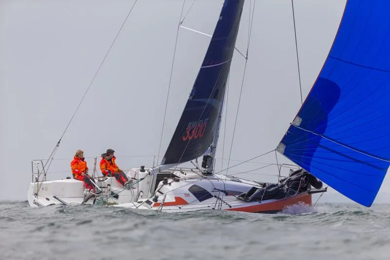 Slide: The Image of 2025 Jeanneau Sun Fast 3300 sailing with vibrant blue spinnaker and crew in orange gear. - 46