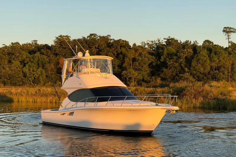 Slide: The Image of 2017 Tiara Yachts 39 Convertible cruising on a serene waterway at sunset. - 10