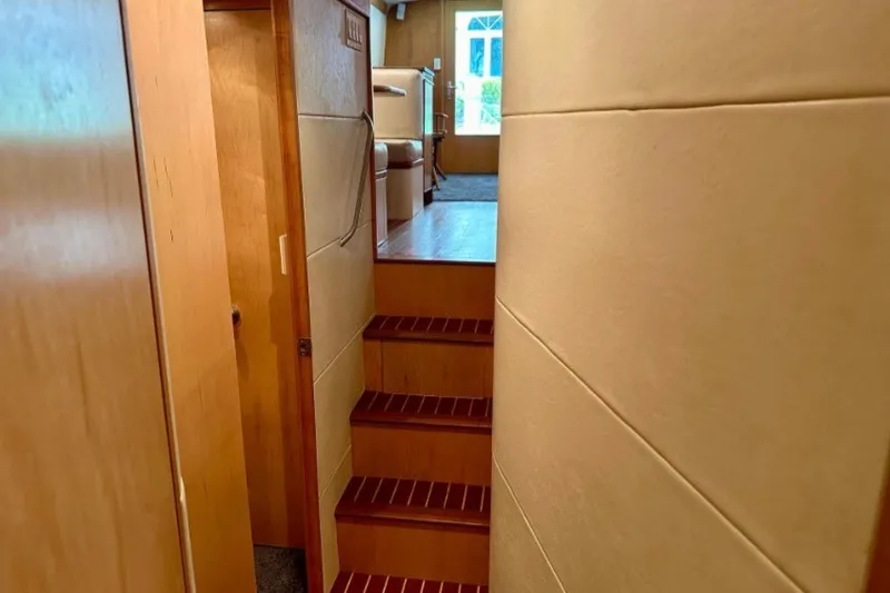 Slide: The Image of Interior view of 1985 Bertram 54 Convertible yacht, featuring wooden stairs and cozy cabin space. - 21