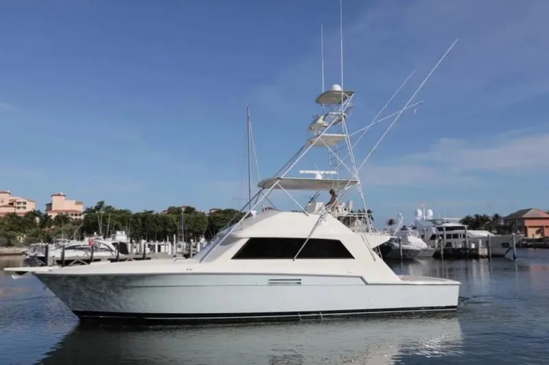 The Image of 1985 Bertram 54 Convertible yacht docked in a marina under clear blue skies. - 0