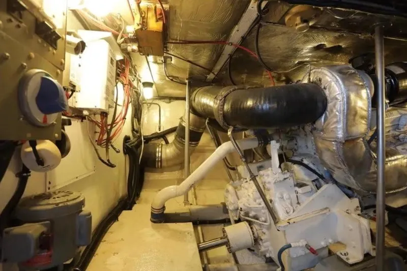 Slide: The Image of Engine room of a 1985 Bertram 54 Convertible yacht, showcasing mechanical components and wiring. - 25