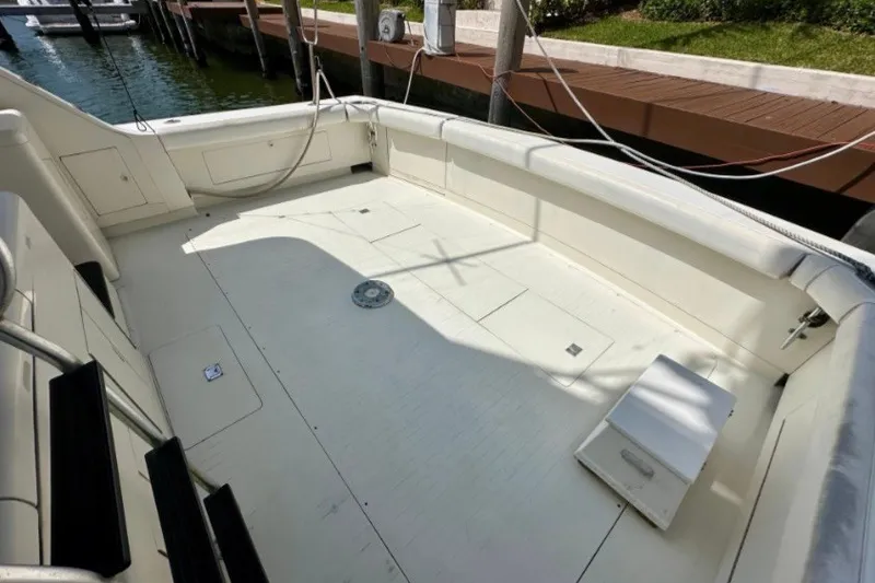 Slide: The Image of 1985 Bertram 54 Convertible boat deck, spacious and well-maintained, docked by the water. - 15