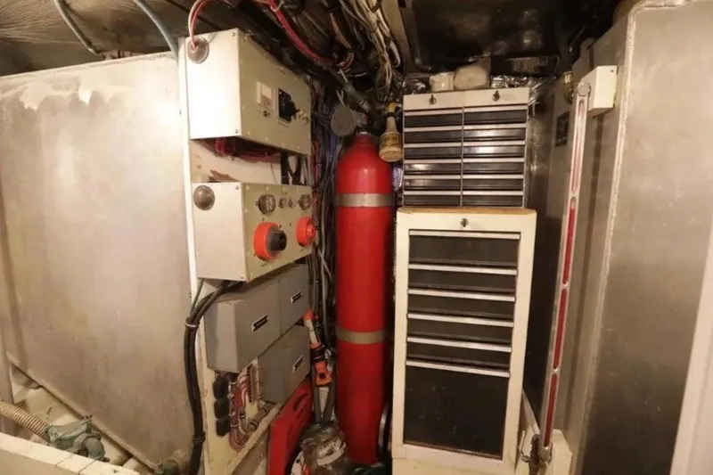 Slide: The Image of Engine room of a 1985 Bertram 54 Convertible yacht with control panels and storage. - 30