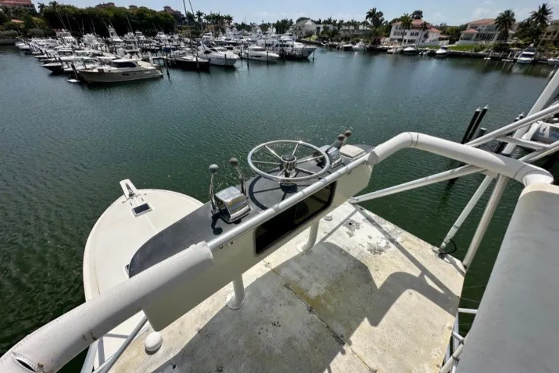 Slide: The Image of Helm of 1985 Bertram 54 Convertible overlooking marina with docked boats. - 13