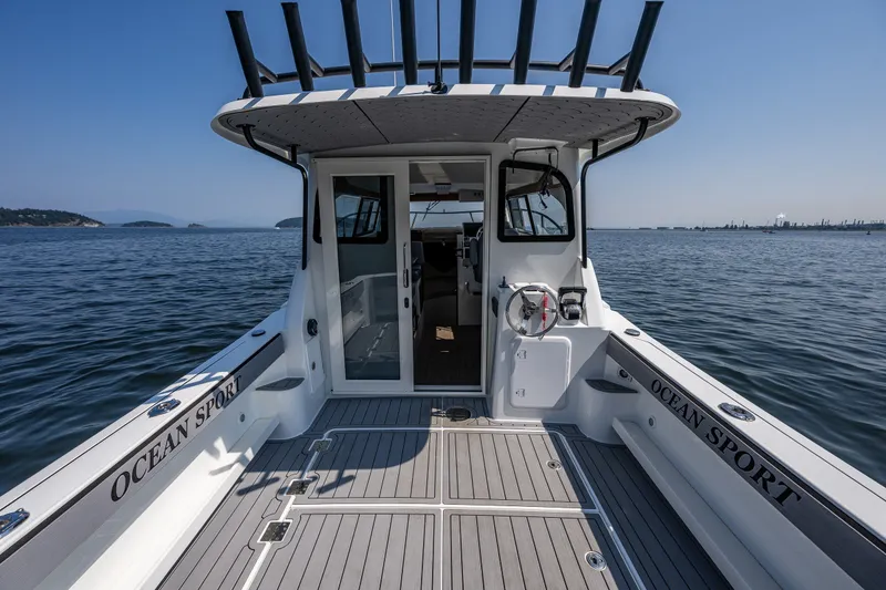 Slide: The Image of 2025 Ocean Sport 27 boat on calm water, showcasing spacious deck and sleek design. - 15