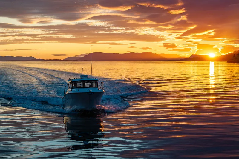 Slide: The Image of Ocean Sport 27 boat cruising at sunset, 2025 model, reflecting vibrant sky on water. - 22