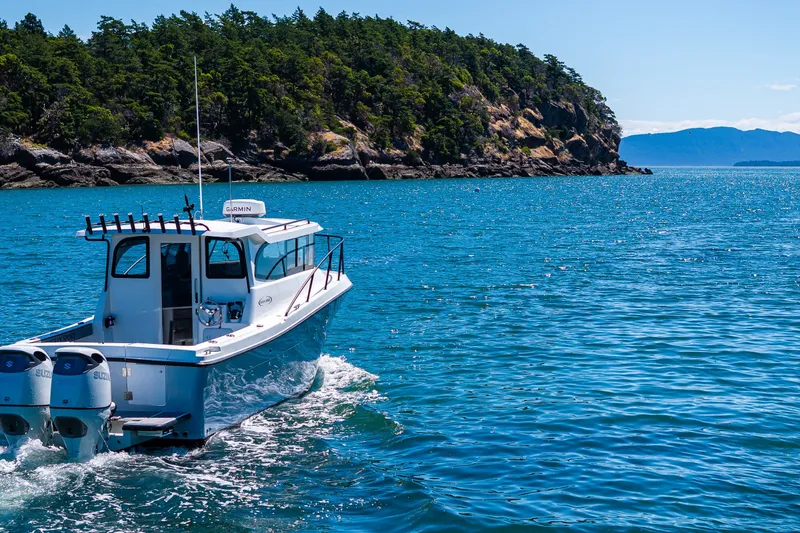 Slide: The Image of Ocean Sport 27 boat cruising in clear blue waters near a forested coastline, 2025 model. - 29