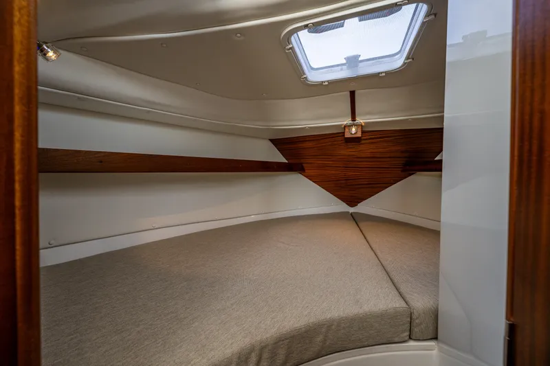 Slide: The Image of Cozy cabin interior of 2025 Ocean Sport 27 boat with cushioned bed and wooden accents. - 13