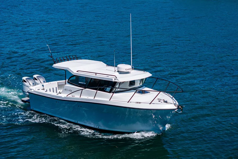 Slide: The Image of Ocean Sport 27 boat cruising on blue water, 2025 model, with twin Suzuki engines. - 33