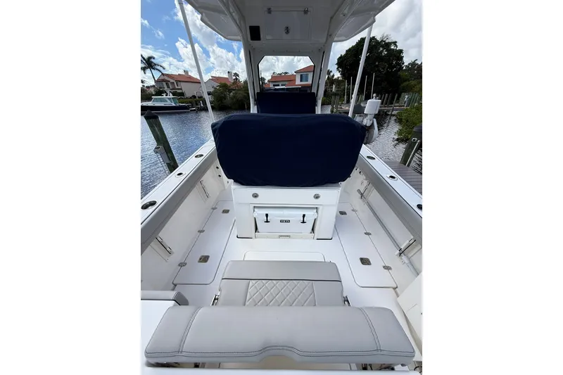 Slide: The Image of 2023 Pursuit S 248 Sport boat interior with seating and storage, docked by waterfront homes. - 9