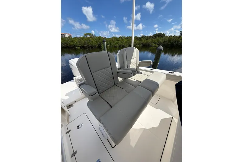 Slide: The Image of 2023 Pursuit S 248 Sport boat seats with gray upholstery, set against a serene water backdrop. - 12