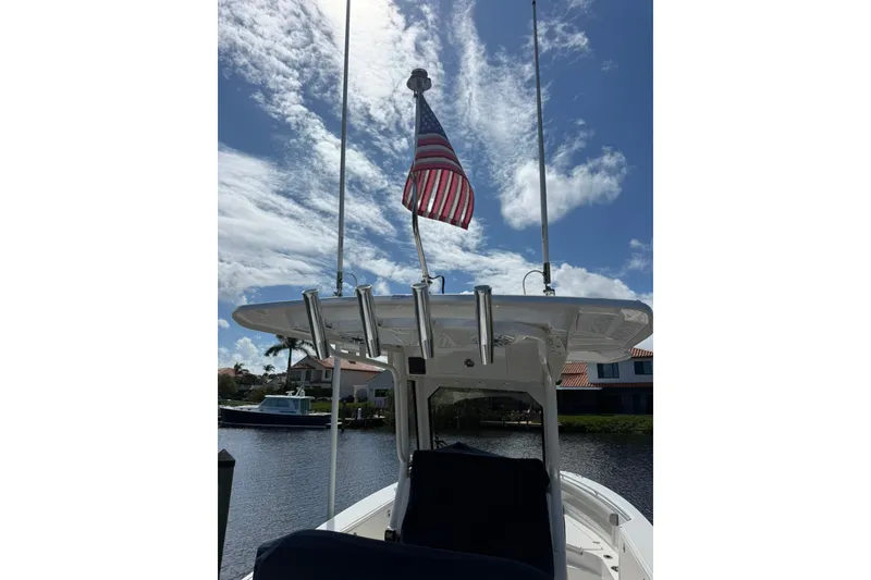 Slide: The Image of 2023 Pursuit S 248 Sport boat with American flag, under a partly cloudy sky. - 31
