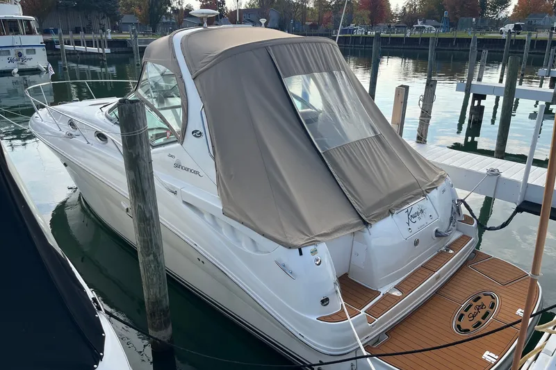 Slide: The Image of 2005 Sea Ray Sundancer 320 docked, featuring a beige canopy and sleek white design. - 2
