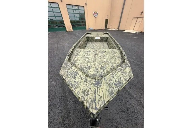 The Image of 2027 Tracker Grizzly 1648 Utility boat with camouflage design, parked outdoors. - 0