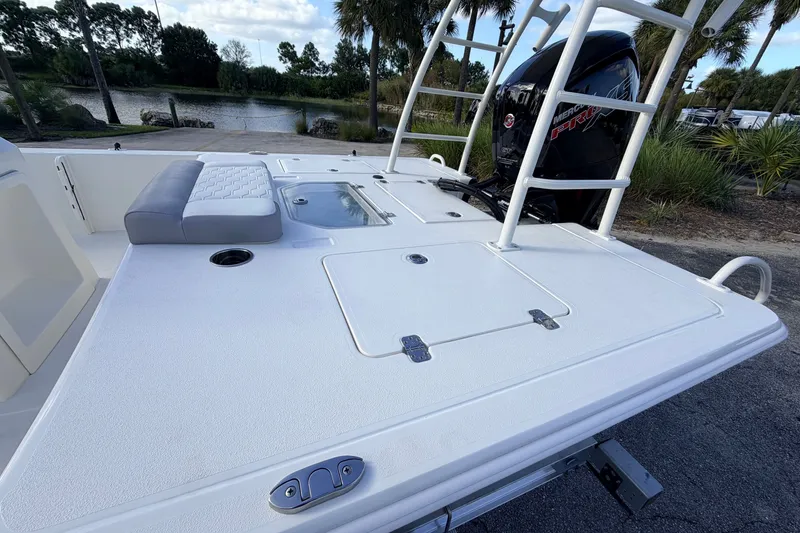 Slide: The Image of 2026 Mako 18 Pro Skiff boat with seating and storage compartments, parked near a lake. - 16