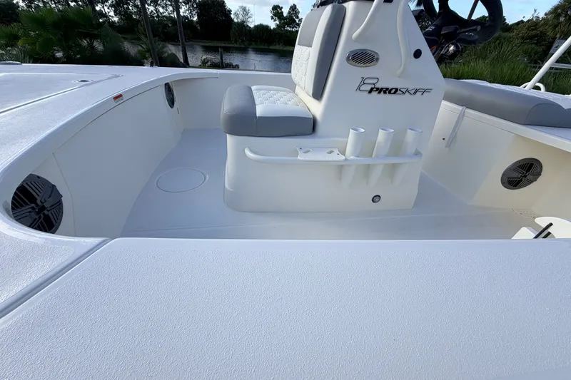 Slide: The Image of 2026 Mako 18 Pro Skiff interior with seating and rod holders, set against a natural backdrop. - 18