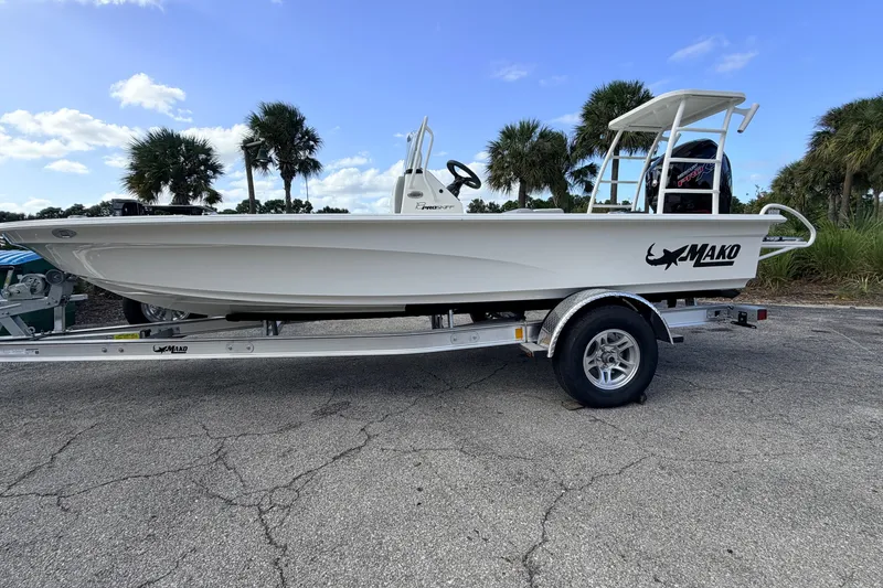 Slide: The Image of 2026 Mako 18 Pro Skiff boat on trailer, parked outdoors with palm trees in background. - 3