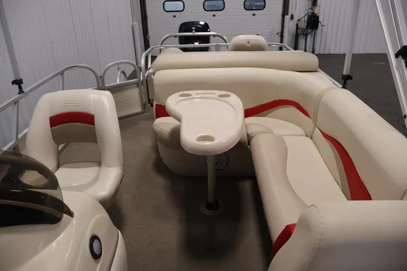 Slide: The Image of 2008 Sun Tracker Fishin' Barge 21 interior with beige and red seating, table, and helm. - 25