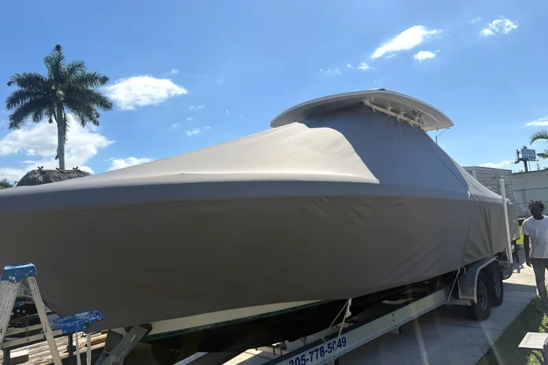 Slide: The Image of 2015 Intrepid 327 Center Console boat covered on trailer under clear blue sky. - 10